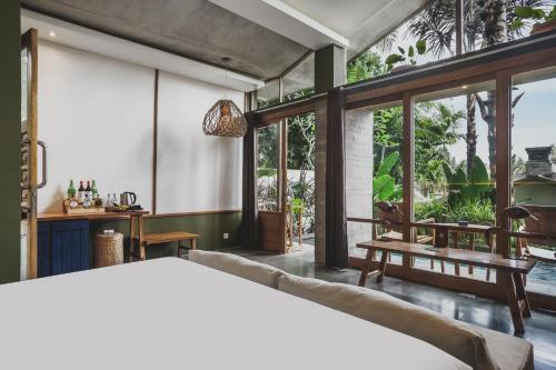 a bedroom with a bed and large windows at Amora Ubud Boutique Villas in Ubud