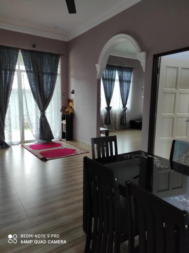 uma sala de estar com uma mesa de jantar e cadeiras em Homestay Anjung Ismail Anjung Rahmah em Kampong Pauh