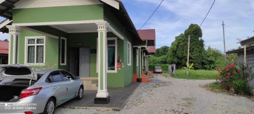 a car parked in front of a green house at Homestay Anjung Ismail Anjung Rahmah in Kampong Pauh
