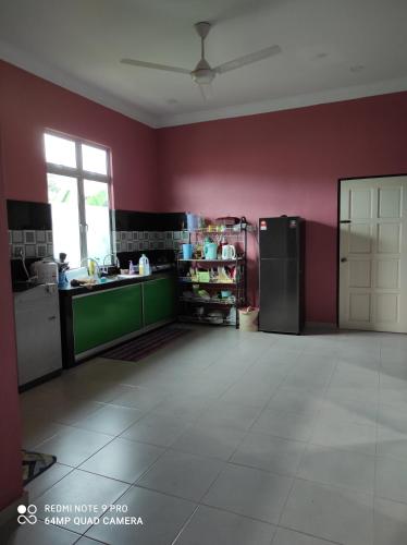 uma cozinha com paredes vermelhas e um frigorífico em Homestay Anjung Ismail Anjung Rahmah em Kampong Pauh