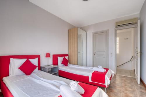 two beds in a room with red and white at Glyfa Corfu Apartments in Barbati