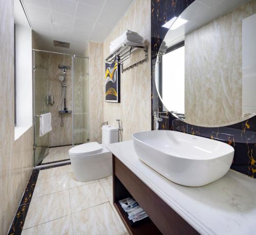 La salle de bains est pourvue d'un grand lavabo blanc et de toilettes. dans l'établissement Diamond Luxury Hotel, à Hạ Long