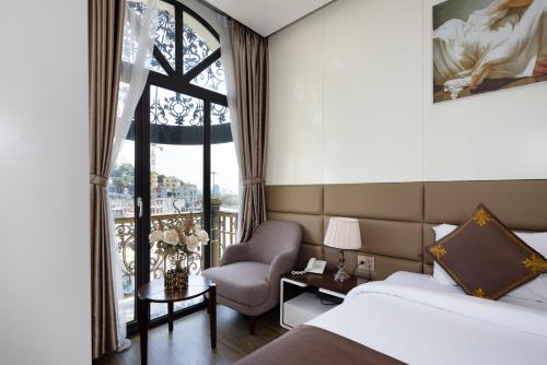 une chambre d'hôtel avec un lit, une chaise et une fenêtre dans l'établissement Diamond Luxury Hotel, à Hạ Long