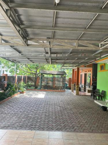 a large patio with a building with a table and chairs at Bu Sur Homestay in Bogor