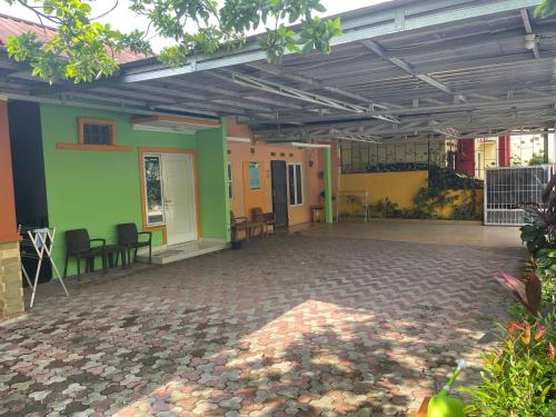 Habitación con paredes verdes y coloridas, mesas y sillas. en Bu Sur Homestay, en Bogor