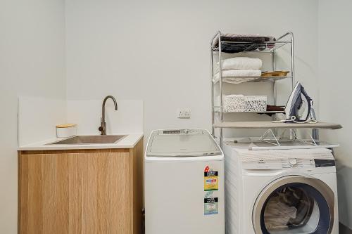 a kitchen with a washing machine and a sink at One16 Tudor in Hamilton