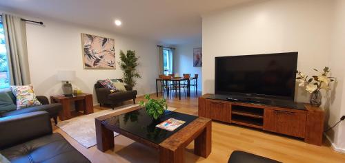 a living room with a large flat screen tv at Grey Gum Getaway in Belgrave