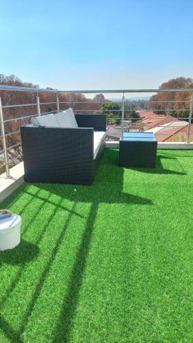 a yard with green grass and two chairs on it at Garden Top Hotel in Johannesburg