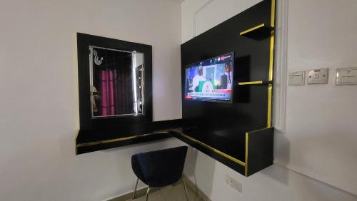 Habitación con TV, espejo y silla. en Palazzo Apartments, en Ikeja