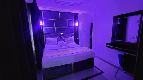 a purple room with a bed and a tv at Palazzo Apartments in Ikeja