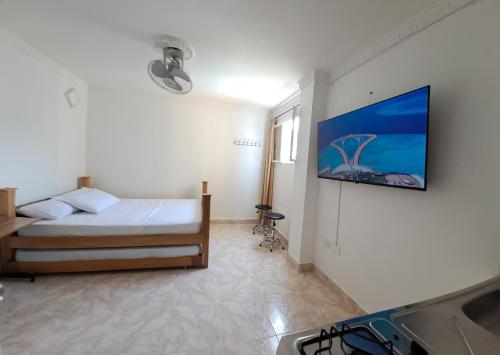 um quarto com uma cama e uma televisão na parede em Luna Azul Rodadero apartaestudios em Santa Marta