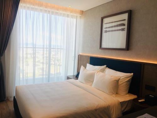 Ce lit se trouve dans une chambre d'hôtel dotée d'une grande fenêtre. dans l'établissement Toà Nhà Apec Mandala Wyndham Phú Yên, à Tuy Hoa