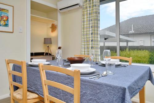 uma mesa de jantar com uma toalha de mesa azul e cadeiras em Charlesworth Villa - Christchurch Holiday Homes em Christchurch