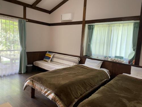 um quarto com 2 camas e uma janela em A private retreat Cotton Club Cottage em Takamori