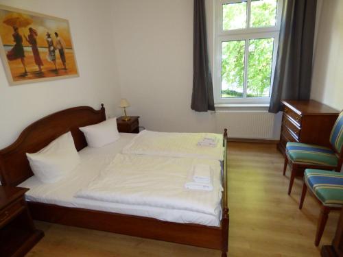 a bedroom with a bed and two chairs and a window at Grosse-Ferienwohnung-Wa2-100qm-im-Erdgeschoss-der-Villa-Walhall-in-einem-parkaehnlichen-Garten in Ostseebad Sellin