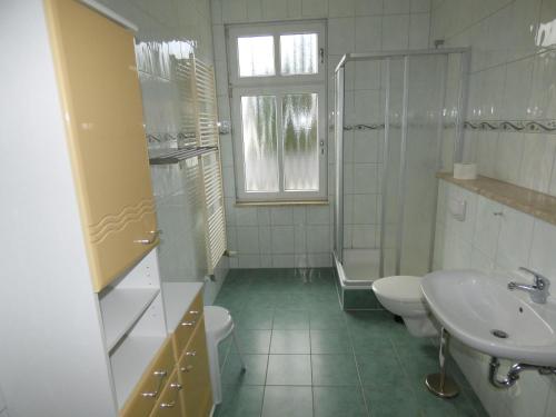 a white bathroom with a sink and a toilet at Sonnige-Ferienwohnung-100qm-im-1-Obergeschoss-der-Villa-Walhall-in-einem-parkaehnlichen-Garten in Ostseebad Sellin
