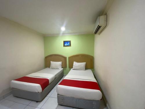 two beds in a room with green and white at HOTEL SAHARA INN BATU CAVES in Batu Caves
