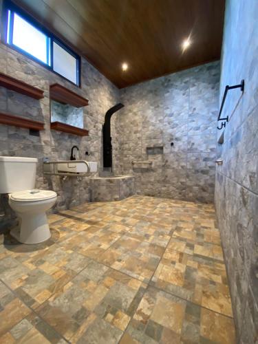 a stone bathroom with a toilet and a sink at Termales del Arenal in Fortuna
