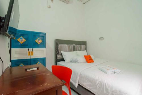 a room with two beds and a table and a desk at KoolKost Syariah @ Citraland Puri Serang in Serang