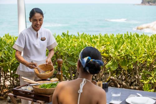 a chef preparing food in front of a woman at Garrya Tongsai Bay Samui in Choeng Mon Beach