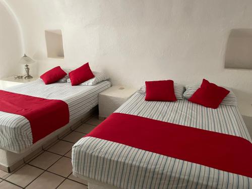 曼萨尼约Condominio Puerto Las Hadas的房间里有两张床，还有红色枕头