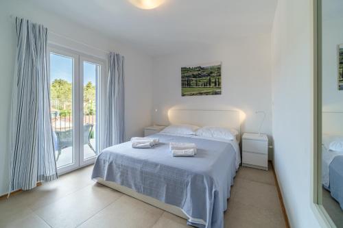 a white bedroom with a bed and a large window at Holiday home Mila - private pool in Milna