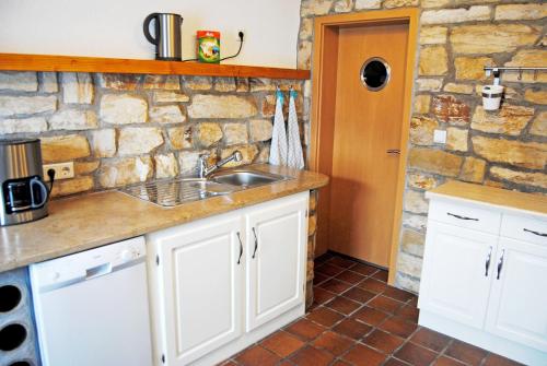 eine Küche mit einem Waschbecken und einer Steinmauer in der Unterkunft Romantik Ferienhaus 1854 in Elpe