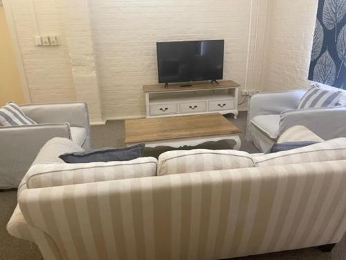 a living room with two couches and a flat screen tv at Gallipoli House- The Loft Apartment in Narrabri