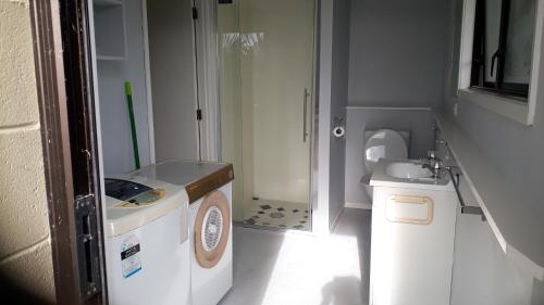 małą łazienkę z pralką i umywalką w obiekcie Pipiroa Bay Homestay w mieście Russell