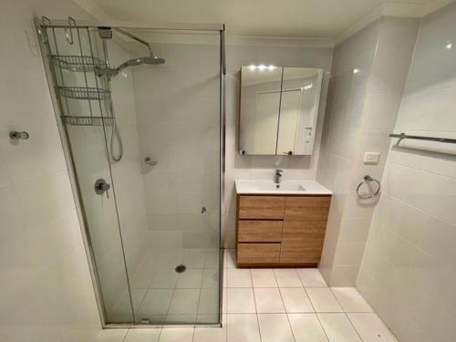 een badkamer met een douche, een wastafel en een spiegel bij Andy & Anna's Weekend Hideaway in Newcastle