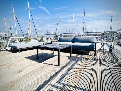 a couch and a table on a deck with boats at Floating Home Nr 1 in Laboe