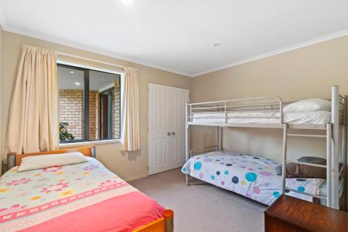 a bedroom with two bunk beds and a window at Bowentown Bach - Waihi Beach Holiday Home in Waihi Beach