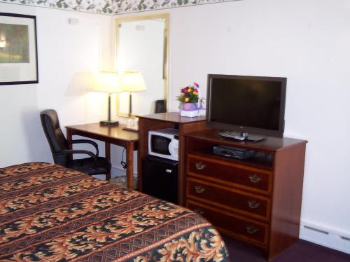 a hotel room with a bed and a flat screen tv at Shore Hills Motel in Manasquan