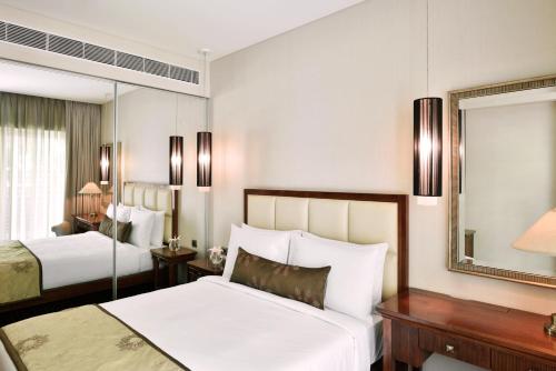 a hotel room with two beds and a mirror at Marriott Suites Pune in Pune