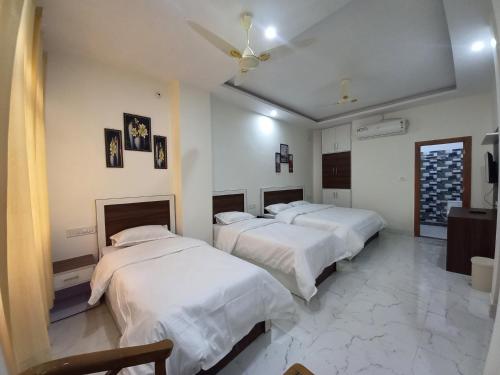 two beds in a room with white walls at Hotel SRP in Rishīkesh