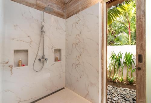 een badkamer met een douche en witte marmeren muren bij Villa Taramille in Kerobokan