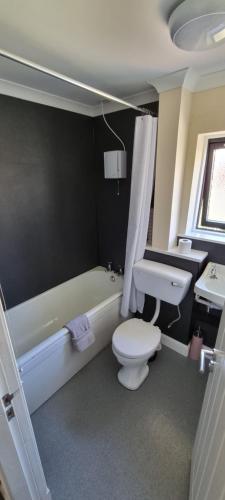 a bathroom with a tub and a toilet and a sink at Benview House in Corpach