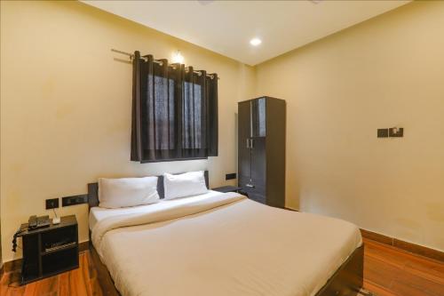 a bedroom with a bed with white sheets and a window at FabHotel Lemon Grass - Assi Ghat in Varanasi