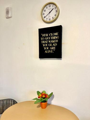 a clock on a wall above a table with a plant at Micro Studio Apartment in University District- 10 mins walk to University of WA in Seattle