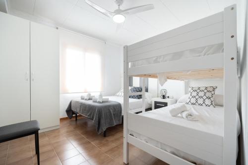 a white bedroom with two bunk beds and a table at Villa Mimosa San Vicente del Raspeig in San Vicente del Raspeig