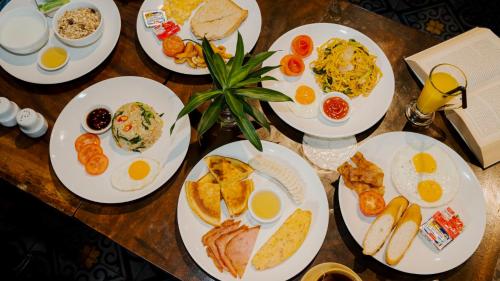 a table with plates of breakfast food on it at Monsoon Bassac Hotel in Phnom Penh