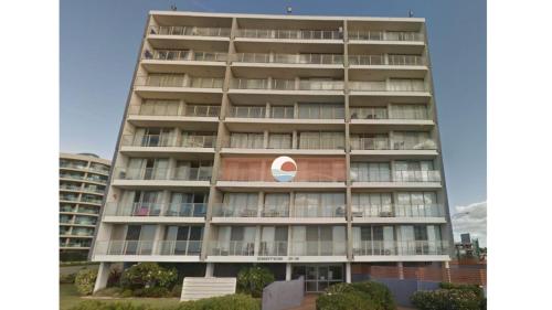 a tall apartment building with a red and white sign on it at Ebbtide 13 in Forster