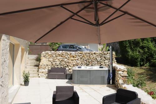 a patio with a table and chairs under a large umbrella at Gîte aux trois suites parentales et son jacuzzi 