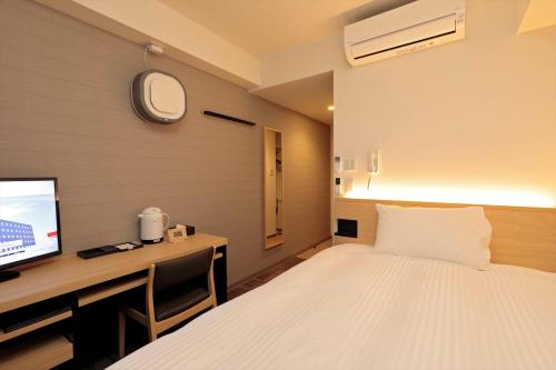 a bedroom with a bed and a desk with a tv at A&Bee HOTEL in Oita