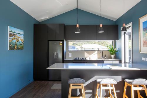 een keuken met blauwe en zwarte kasten en krukken bij Silvan Forest Pod 2 in Richmond