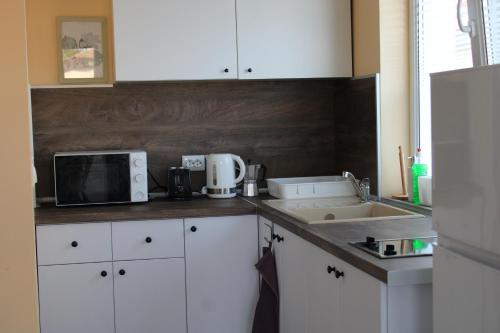 a kitchen with white cabinets and a sink and a microwave at Къща за гости Света Марина in Krapets