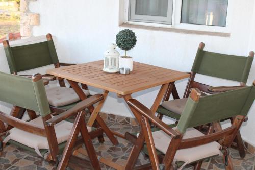 a wooden table with four chairs and a table with a plant at Къща за гости Света Марина in Krapets