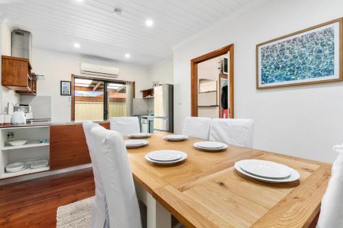 a kitchen and dining room with a wooden table and chairs at Coral Haven - Aldinga Beach - C21 SouthCoast Holidays in Aldinga Beach