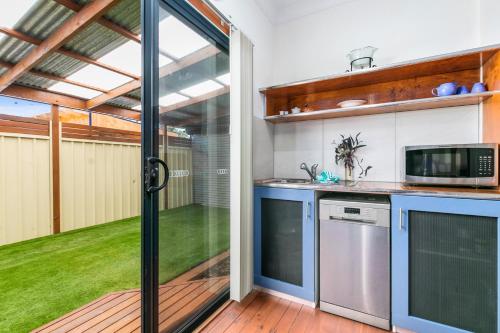 a kitchen with a sliding glass door leading to a yard at Coral Haven - Aldinga Beach - C21 SouthCoast Holidays in Aldinga Beach