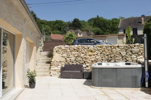 a backyard with a hot tub and a stone wall at Gîte aux trois suites parentales et son jacuzzi 